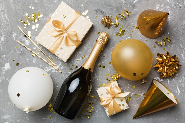 Flat lay composition of Champagne bottle gift box ribbons and confetti on colored background Flat lay top view holiday concept