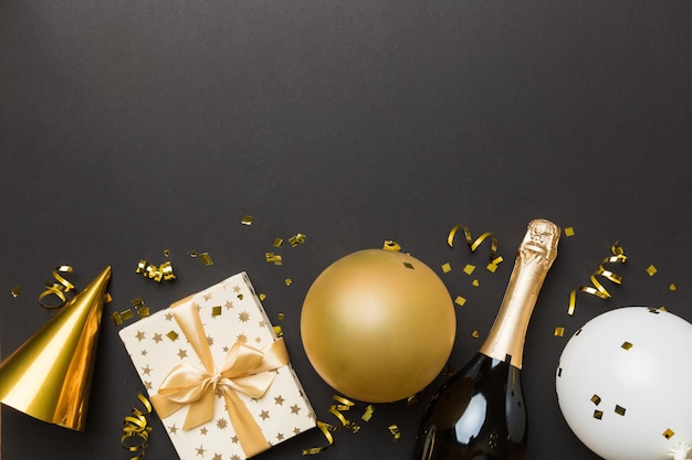 Flat lay composition of Champagne bottle gift box ribbons and confetti on colored background Flat lay top view holiday concept