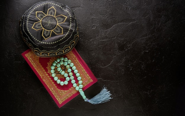 Flat lay composition of holy book for muslim Quran, rosary beads and pray hat
