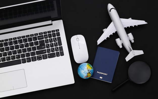 Flat lay composition of laptop and travel accessories on black background. Tourism. Top view.