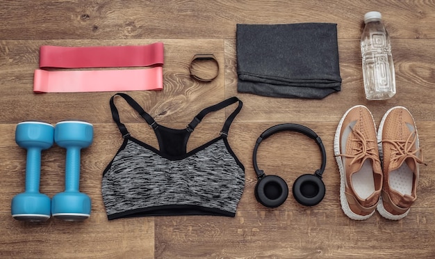 Flat lay composition of Sports equipment, clothes on a wooden floor. Fitness, sport and healthy lifestyle concept. Top view