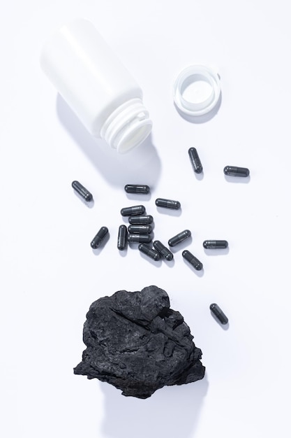 Flat lay composition of vegetable carbon capsules on white background Vertical format Dietary supplements concept