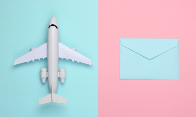 Photo flat lay composition with airplane figure and envelopes of letters on pink blue pastel.