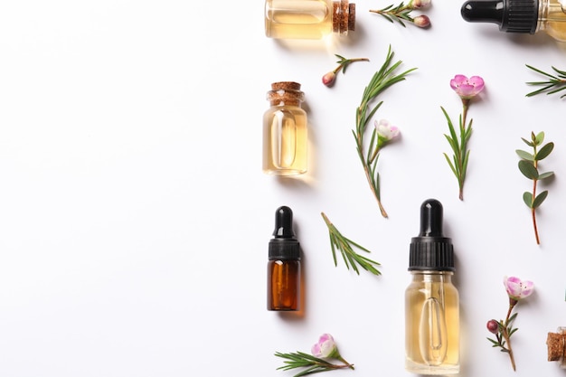 Photo flat lay composition with bottles of natural tea tree oil on white background