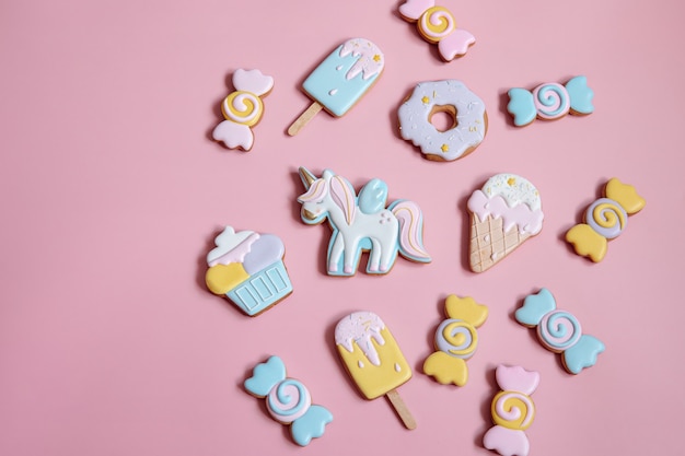 Flat lay composition with bright glazed gingerbread cookies on pink background.