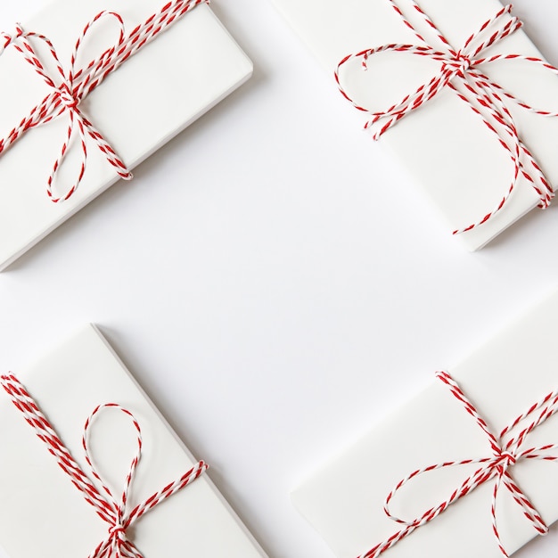 Flat lay composition with Christmas gifts boxes with red ribbon on white