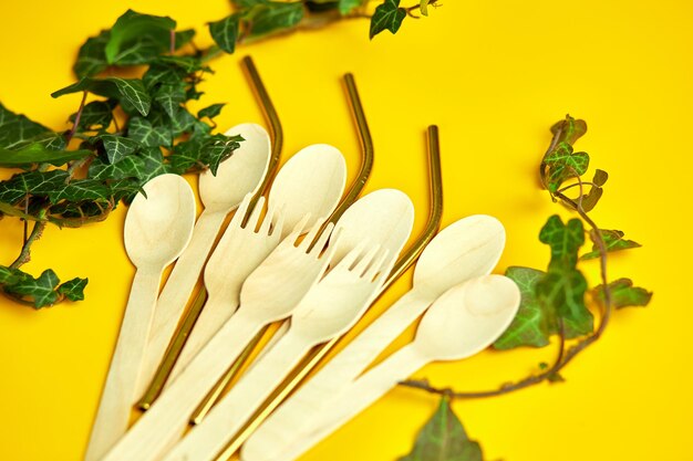 Flat lay composition with colored healthy vegan gummy bears in eco wooden spoon with green leaves on yellow background vitamins healthy candies top view copy space