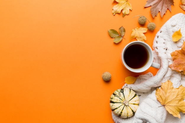 Flat lay composition with colorful autumn cup of coffee and\
leaves on a color background top view