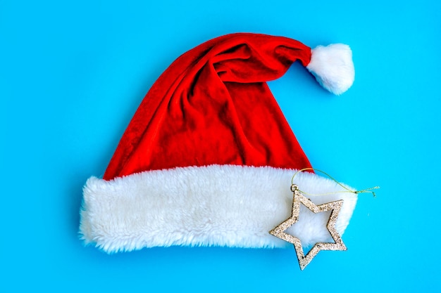 Flat lay composition with cotton pads and red Christmas hat on blue background Top view Kids Christmas Tree Craft DIV