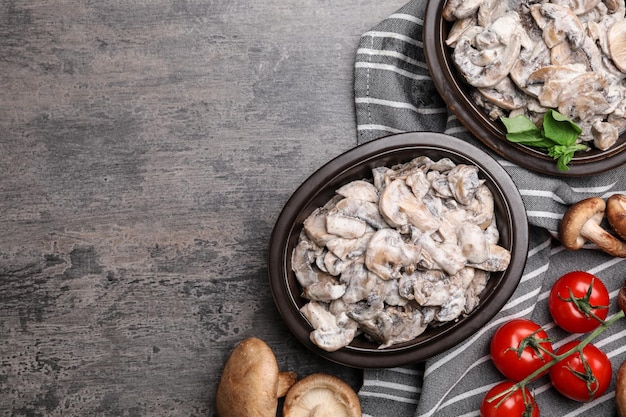 Flat lay composition with delicious cooked mushrooms on grey table Space for text