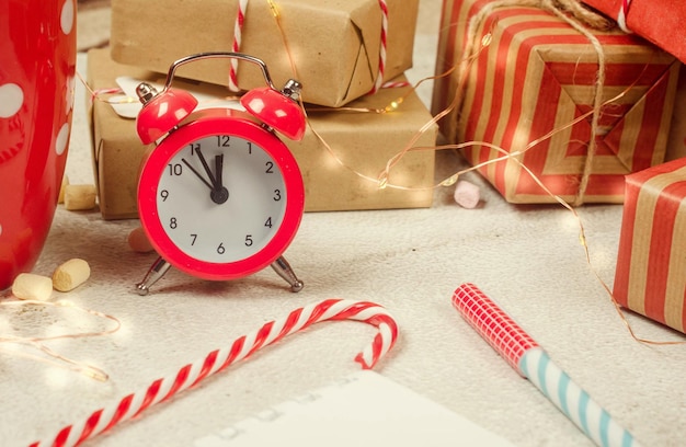 Flat lay composition with diary book for writing down New Year's plans with red Christmas  decorations, cup of cocoa with marshmallows, alarm and gifts. Planing New Year. Goals in notebook