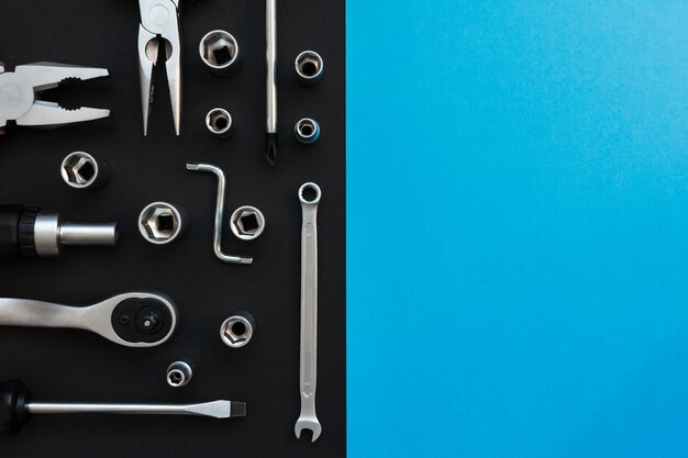 Flat Lay Composition With Different Construction Tools on Black and Blue Background. Top View of Checklist and Working Tools, Wrench, Screwdriver, Plier.