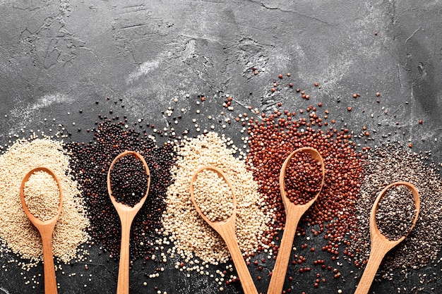 Flat lay composition with different types of quinoa on black background.  Top view.