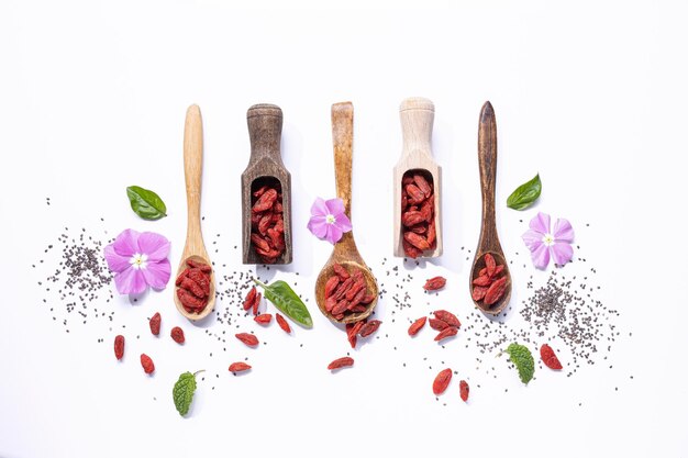 Photo flat lay composition with dried goji berries on wooden spoons on white background