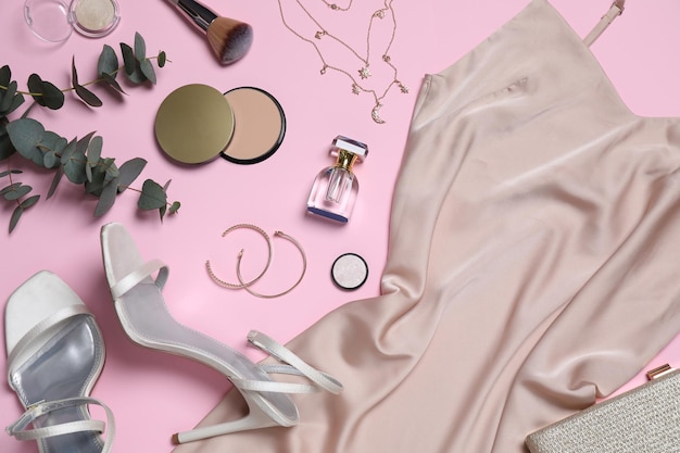 Flat lay composition with elegant beige dress and women39s accessories on pink background