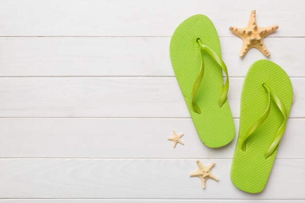 Flat lay composition with flip flops and seashell on colored background Space for text top view