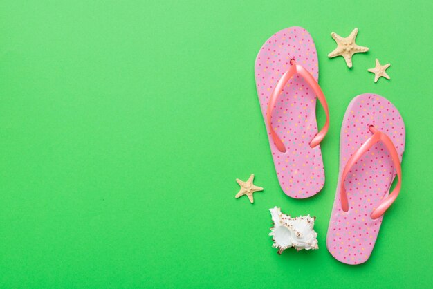 Flat lay composition with flip flops and seashell on colored background Space for text top view