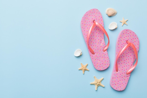 Flat lay composition with flip flops and seashell on colored background Space for text top view