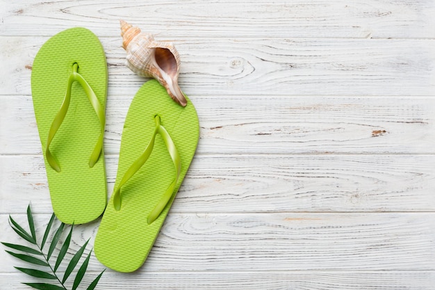 Flat lay composition with flip flops and seashell on colored background Space for text top view