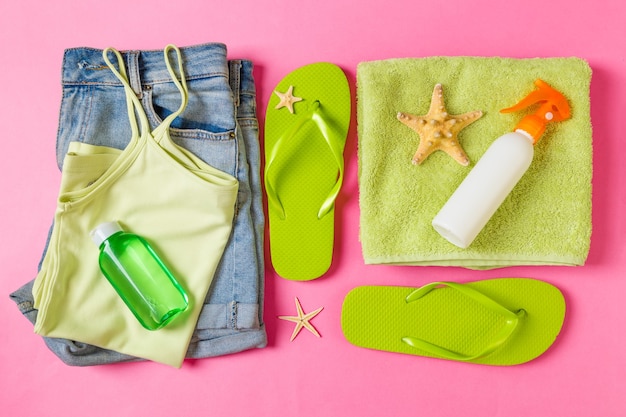 Flat lay composition with green Beach accessories on pink or coral color background