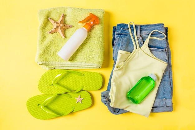 Flat lay composition with green Beach accessories on yellow color background. Summer holiday background. Vacation and travel items top view.