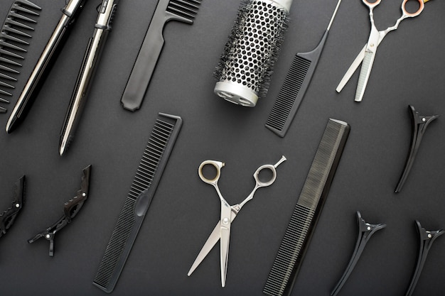 Flat lay composition with Hairdresser tools scissors, combs, hair iron on black