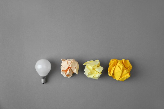 Photo flat lay composition with lamp bulb and crumpled paper on grey background