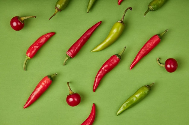 Flat lay composition with many hot chili peppers on green background