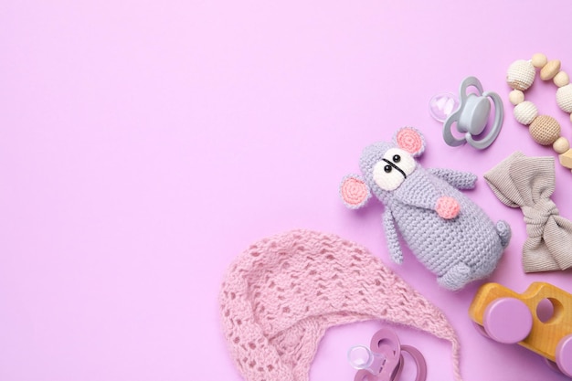 Flat lay composition with pacifiers and other baby stuff on violet background Space for text