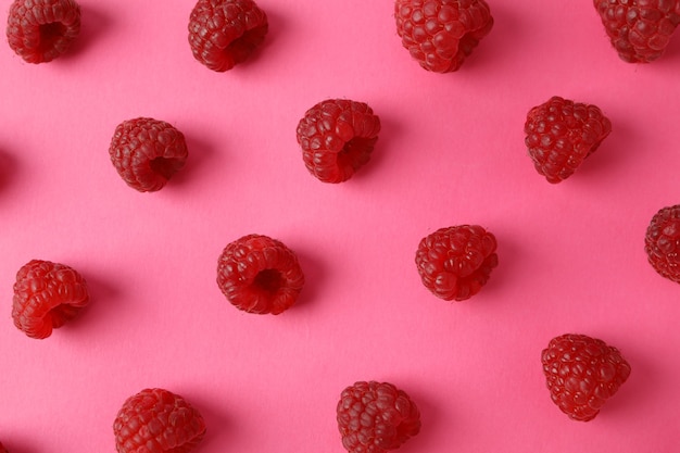 Flat lay composition with red juicy raspberries on a pink background