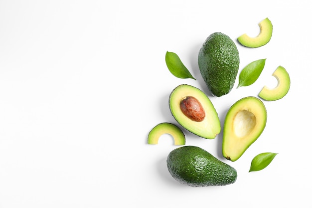 Photo flat lay composition with ripe avocados and leaves on white