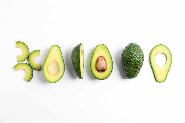 Photo flat lay composition with ripe cut avocados on white