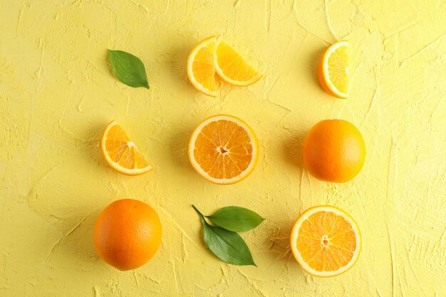 Flat lay composition with ripe oranges and leaves on color background. Top view