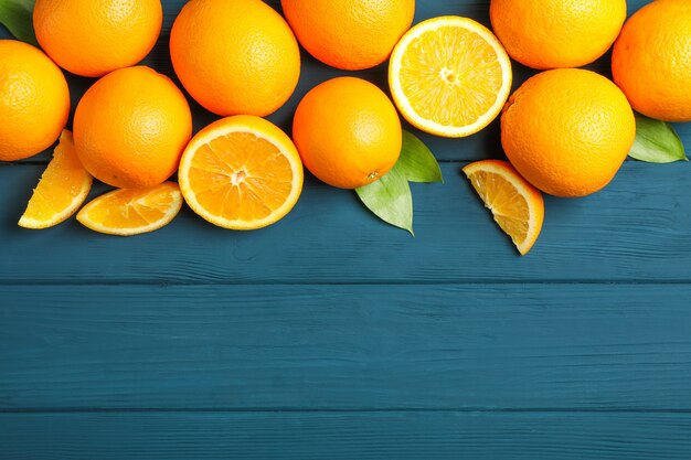 Flat lay composition with ripe oranges and leaves on wooden background. top view, space for text