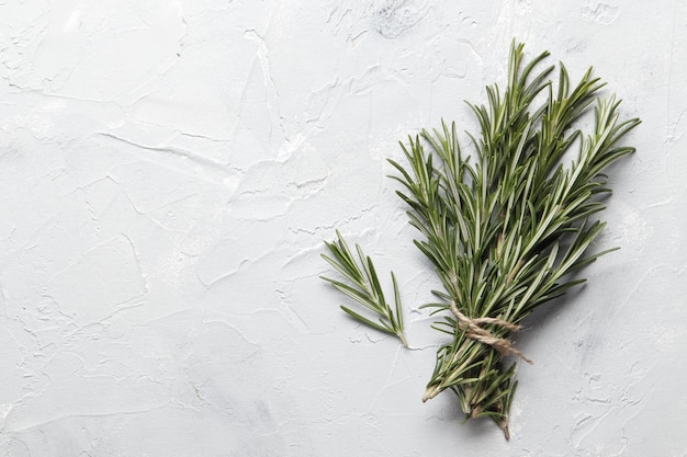 Flat lay composition with rosemary on white concrete background, space for text
