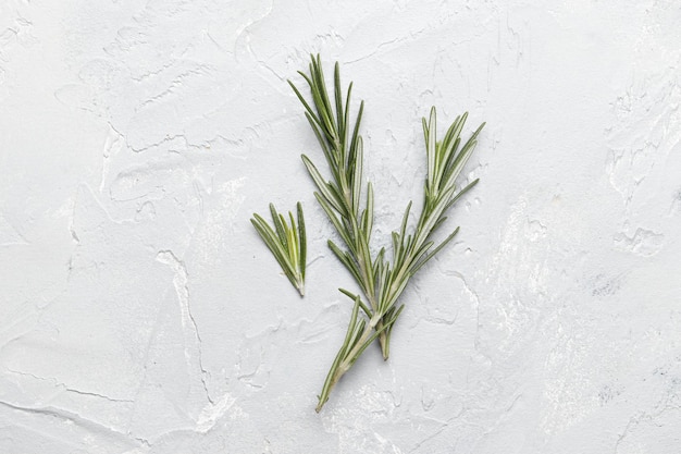 Flat lay composition with rosemary on white concrete background, space for text