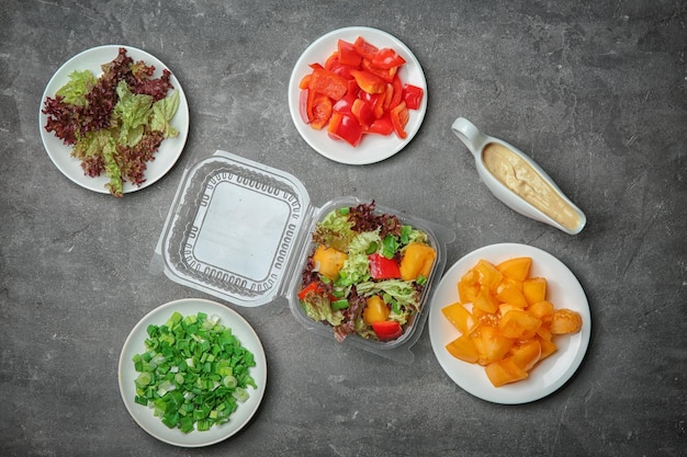 Photo flat lay composition with salad and ingredients on grey background