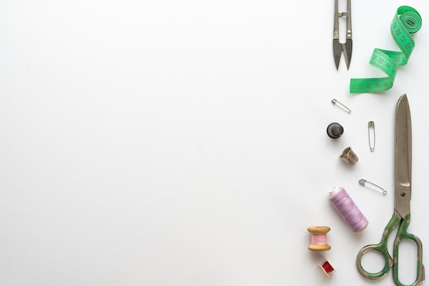 Flat lay composition with scissors and other sewing accessories on white background. Space for text