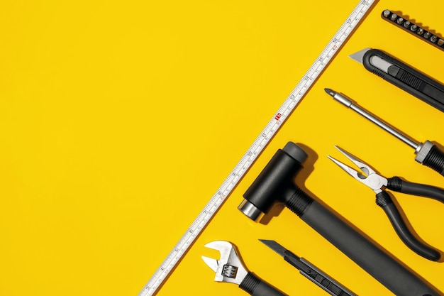 Flat lay composition with set of home repair tools on bright yellow background