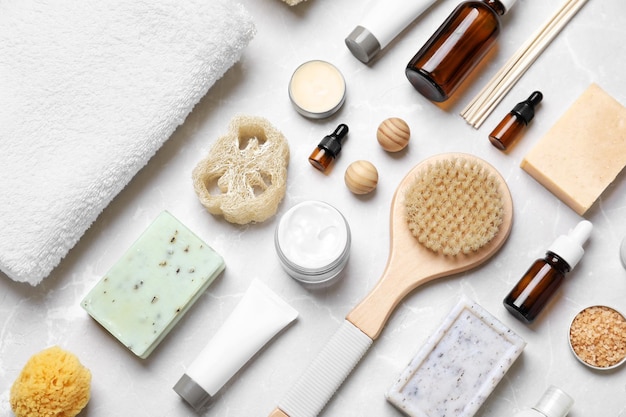 Flat lay composition with spa cosmetics and towel on light background