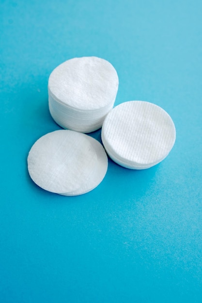 Flat lay composition with stack of cotton pads on blue background Space for text close up Image with selective focus noise effect and toning Top view