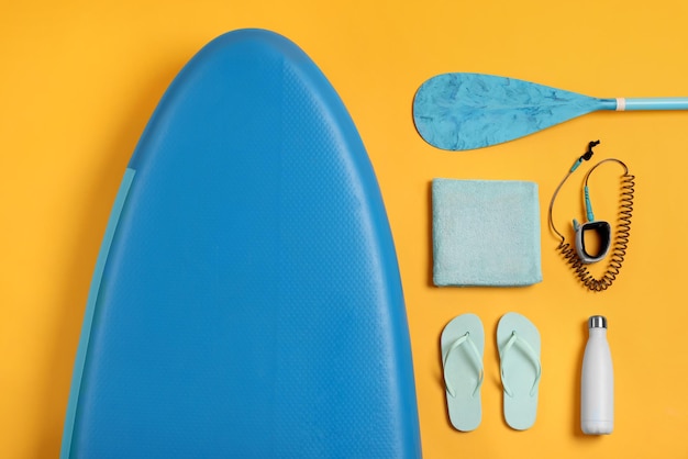 Flat lay composition with sup board on yellow background water sport