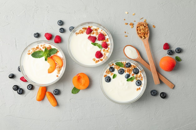 Photo flat lay composition with yogurt desserts and fruits on grey cement background