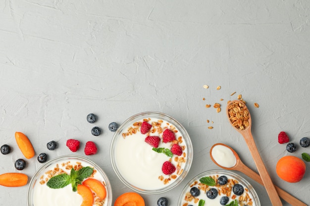 Flat lay composition with yogurt desserts and fruits on grey cement background