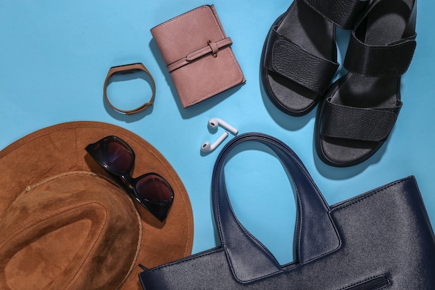 Flat lay composition of women's accessories on a bright blue background. Stylish fashion concept or travel. Top view