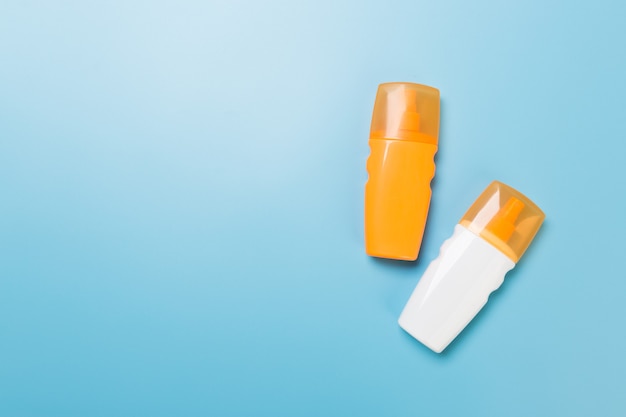 Flat lay concept of summer travel vacation. Sunscreen bottle mock up on blue background top view with copy space.
