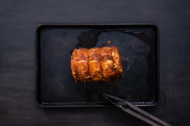 Flat lay. Cooked boneless pork roast seasoned with spices on baking sheet.