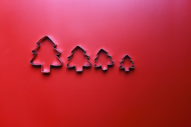 Flat lay cookie cutters in the form of Christmas trees on a red background Christmas mood