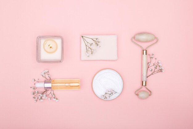 Flat lay of cosmetic products and hygiene items and dry flowers on a pink background Concept of body and face care View from above