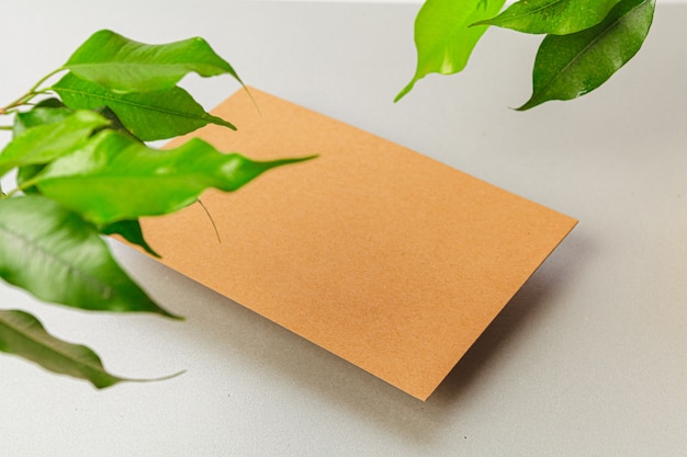 Flat lay craft paper card mockup with leaves, top view